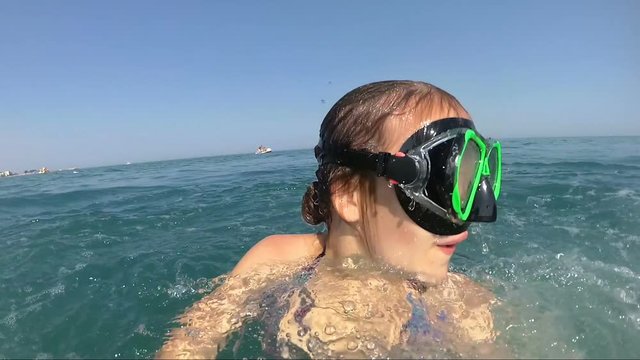 girl on pedal boat pulls off the hill into the sea, view from water, outdoors