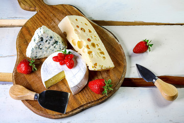 Assorted cheeses on wooden board. Camembert, cheese with blue mildew, gouda, hard cheese,...
