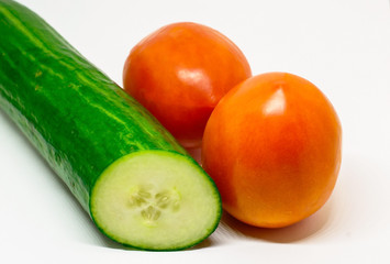 Two ripe red juicy tomatoes and a green cucumber on a white background