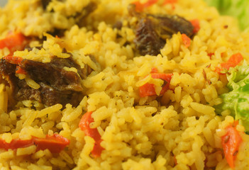 Uzbek pilaf with lamb, spices and seasonings, decorated with lettuce leaves on a wooden background