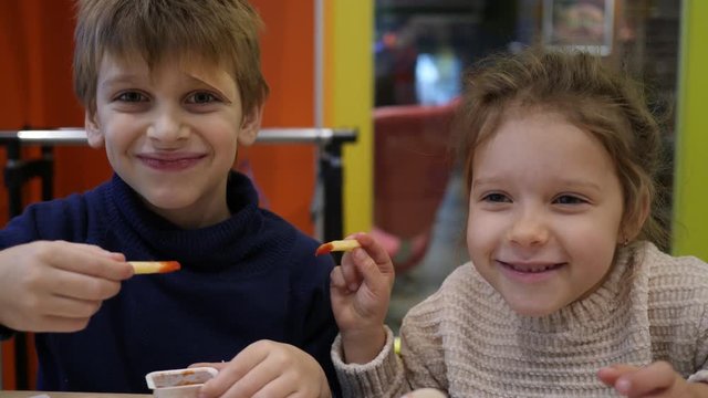Fast food restaurant children boy and girl funny eat feed each other french fries potatoes