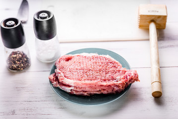 Raw pork on a blue plate on a white table