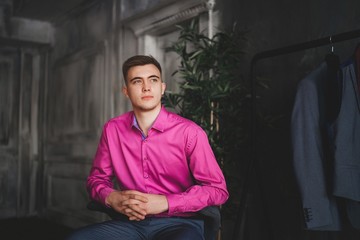 A young man in a pink shirt and a suit.