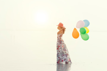 motivation or hope concept, follow your dream and inspiration, girl with balloons at sunset