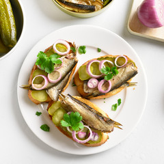 Sandwiches with sprats, marinated cucumber and onion