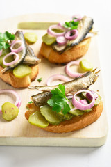 Sandwiches with sprats, marinated cucumber and onion