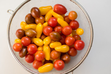 Colorful, healthy foods.Clean, fresh, washed Colorful Cherry tomatoes in a colander. Drops of water on vegetables. Important to wash vegetables before eating concept.