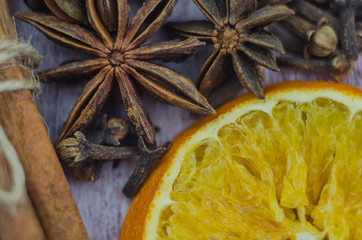 Hot mulled wine drink with lemon, apple, cinnamon, anise and other spices in a glass cup between fir tree branches on wooden cutting board