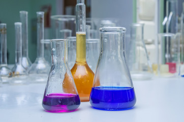 Laboratory glassware with multi-colored liquid on table. Chemical analysis