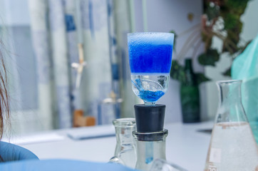 a chemist holds a glass test tube in his hand, overflows a liquid solution, conducts an analysis reaction using various reagent options using chemical production.