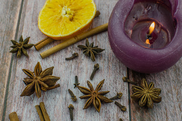 Hot mulled wine drink with lemon, apple, cinnamon, anise and other spices in a glass cup between fir tree branches on wooden cutting board