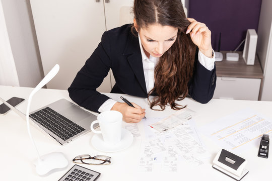   Young attractive business woman working at desk sorting receipts doing expenses paperwork