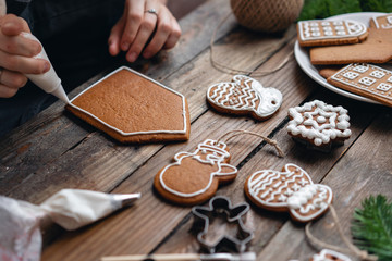 A lot of ginger biscuits in different form on brown wooden table. Decorated with white sweet glaze. Christmas mood, winter morning. Fir branches