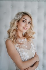 Beautiful blonde bride in a modern dress posing in the Studio. Morning newlyweds.