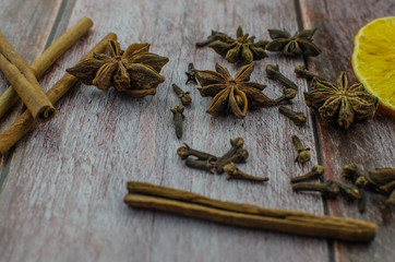 Hot mulled wine drink with lemon, apple, cinnamon, anise and other spices in a glass cup between fir tree branches on wooden cutting board