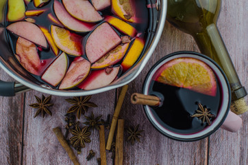 Hot mulled wine drink with lemon, apple, cinnamon, anise and other spices in a glass cup between...