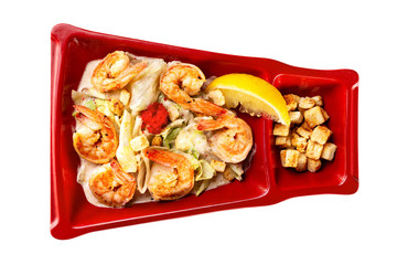 Plate of asian salad with grilled prawns, chicken breast, lemon and croutons isolated at white background.