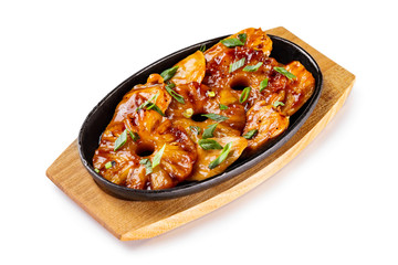 Pan of fried chicken fillet with pineapple rings and onion served with teiyaki sauce at wooden board isolated at white background.