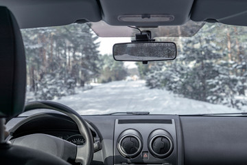 Inside view from car vehicle at snowy road in forest. Winter off road trip.