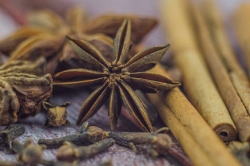Hot mulled wine drink with lemon, apple, cinnamon, anise and other spices in a glass cup between fir tree branches on wooden cutting board