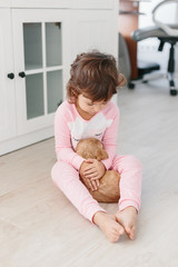Cute little girl playing with dog english cocker spaniel puppy at home.
