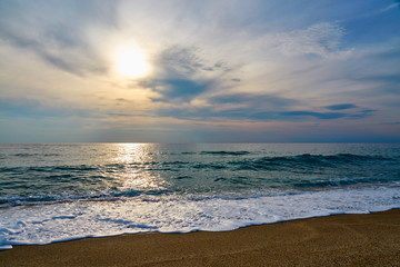 Fototapeta na wymiar Sunset at the beach, waves with foam hitting sand.