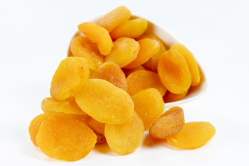 Tasty dried apricots in a white bowl. Treats for cakes on the kitchen table.