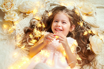 girl child is lying with christmas lights and flowers, face closeup