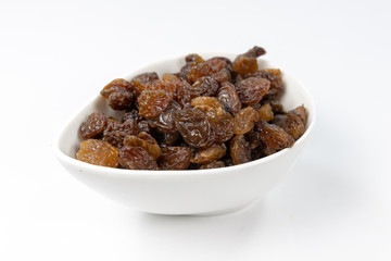 Tasty raisins in a white bowl. Treats for cakes on the kitchen table.