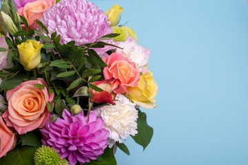 beautiful floral arrangement, pink and yellow rose, pink eustoma, green and pink chrysanthemum, white carnation, pink dahlia on a blue, turquoise background with space for text.