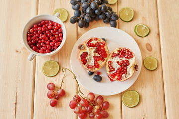 pomegranate, grapes, lime and cranberries on a wooden surface