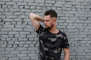 Handsome attractive young man in a stylish camouflage military gray T-shirt with a stylish...