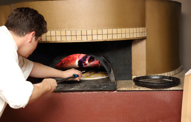 Piekarz wkłada pizzę do pieca.	