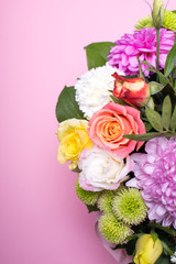 beautiful floral arrangement in the box, pink and yellow rose, pink eustoma, green and pink chrysanthemum, white carnation, pink dahlia on pink background with space for text.