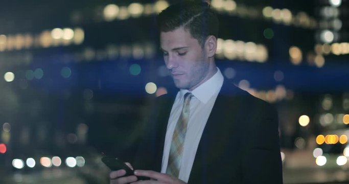 Businessman using smartphone outdoors at night with bokeh effect