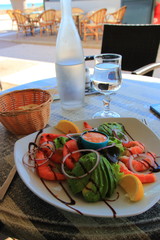 Plate of avocado, shrimps and raw vegetables with sauces on the table of a french restaurant