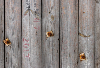 wooden background in gray with inscriptions and iron bolts.