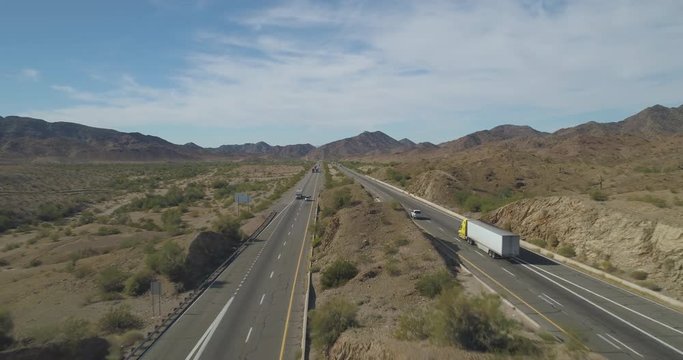 Flying overhead and along interstate 10 in the Arizona desert between Phoenix and Los Angeles with blue skies and mountains.