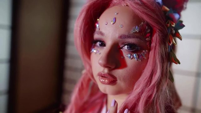 close-up portrait of young caucasian unconventional geisha girl with pink locks, crystals on face