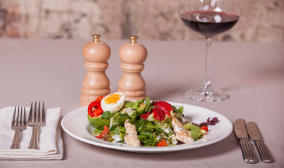 salad with chicken, egg and strawberries. Serving. Red wine