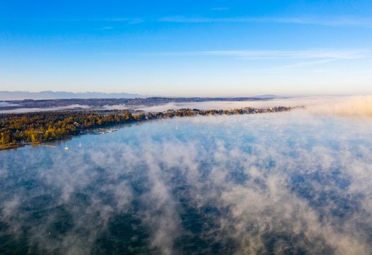 Morning fog over Lake Starnberg with view on Seeshaupt near Munsing, drone shot, Funfseenland, Upper Bavaria, Bavaria, Germany, Europe
