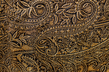 Texture of golden brown genuine leather close-up, with embossed floral trend pattern, wallpaper or...