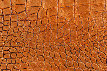 Texture of orange brown genuine leather close-up, with embossed scales reptiles, fashion trend...