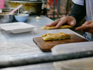 Fototapeta na wymiar Crisp fresh chopped roti being put in a box getting ready to be served - delicious street food in Thailand
