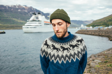 Portrait of handsome young man with beard in green hat and blue knit woolen sweater. Concept...