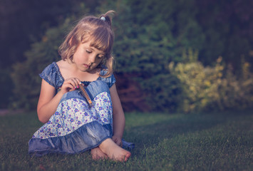 Sad girl with harmonica sitting in a garden