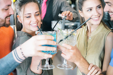 Happy friends cheering with cocktails in a bar outdoor - Young millennial people having fun drinking alcohol and laughing together - Youth lifestyle party concept