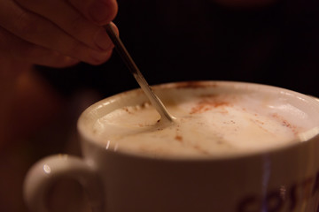 A man's hand mixing with spoon of latte