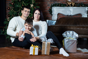 Christmas photo of happy family around a decorated Christmas tree. Family celebrates New year