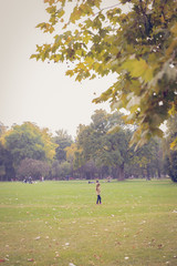 A young girl standing alone in the park. An autumn Sunday view at a public park